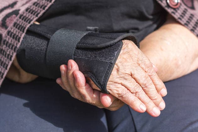 Nahaufnahme älterer Frauen Hände mit sichtbaren Falten tragen schwarze orthopädische Handgelenkstrebe, Konzept der Verletzungsrückgewinnung, Arthritis-Behandlung und Gesundheitsunterstützung für Senioren Close up of elderly woman hands with visible wrinkles wearing black orthopedic wrist brace, concept of injury recovery, arthritis treatment and healthcare support for senior people (License=RF) ,model released, Symbolfoto Copyright: xZoonar.com EvgeniiaxGordeevax 25011903 ,model released, Symbolfoto ,property released