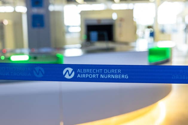 Opening of the new CT control center at Nuremberg Airport, Nuremberg, 08 05 2026 Barrier tape with the logo of Albrecht Dürer Airport Nuremberg in front of the new CT control center In the background, blurred areas of passenger control with modern scanner technology can be seen Nuremberg Bavaria Germany 20260508-286A6802-M4000