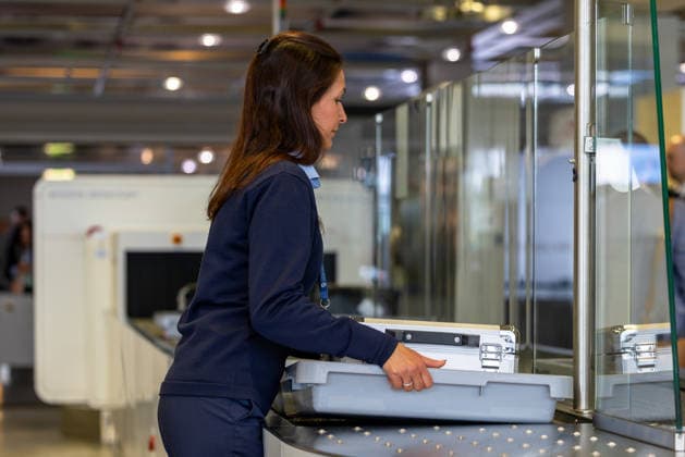Opening of the new CT checkpoint at Nuremberg Airport, Nuremberg, 08 05 2026 An employee moves a baggage tray with a transport case on the conveyor system of the new CT checkpoint at Nuremberg Airport A CT scanner from Smiths Detection can be seen in the background Nuremberg Bavaria Germany 20260508-1V9A7947-M4000