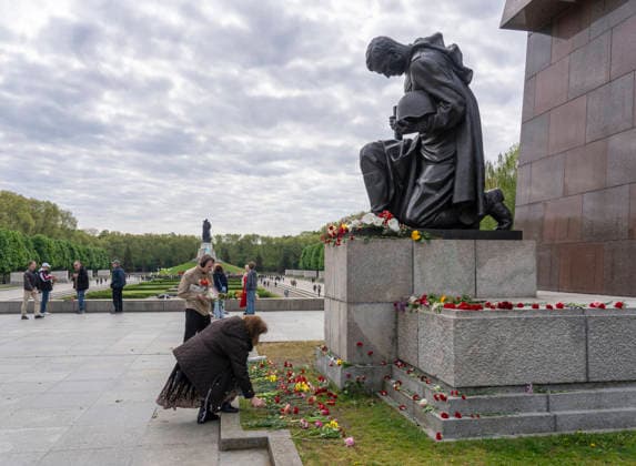 Visitors lay flowers at the kneeling Red Army soldier on May 9, Victory Day, at the Soviet Memorial in Treptower Park in Berlin Treptow
