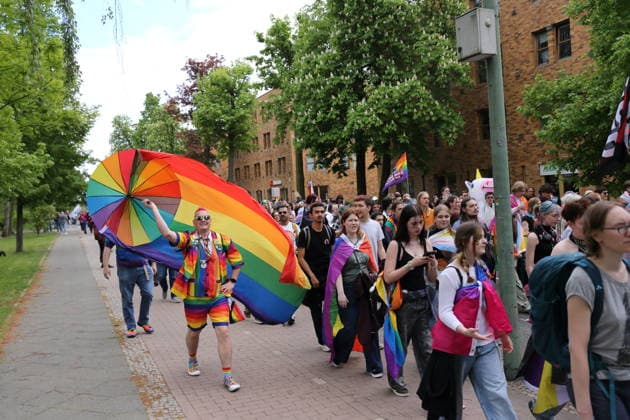 People walk with a rainbow flag in the Pappelallee during a demonstration for Christopher Street Day in Potsdam, May 9, 2026 CSD in Potsdam