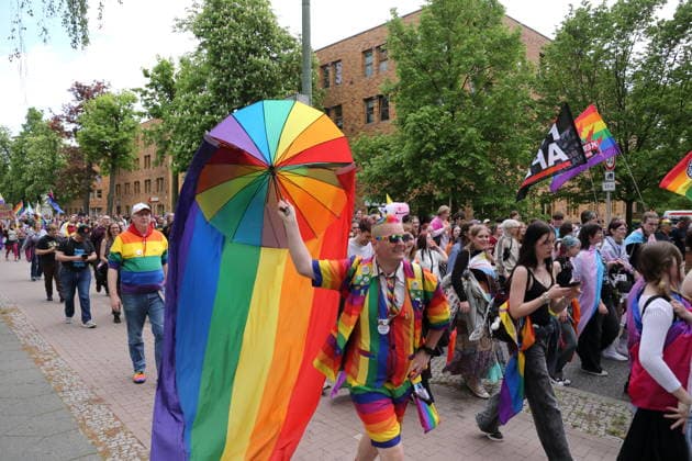 People walk with a rainbow flag in the Pappelallee during a demonstration for Christopher Street Day in Potsdam, May 9, 2026 CSD in Potsdam