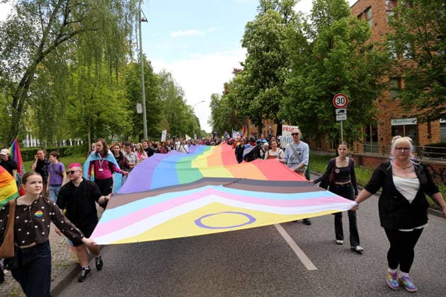 People walk with a rainbow flag in the Pappelallee during a demonstration for Christopher Street Day in Potsdam, May 9, 2026 CSD in Potsdam