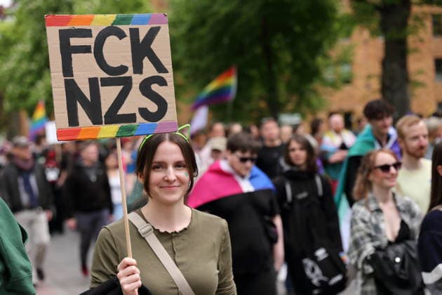A person walks with a sign FCK NZS in the Pappelallee during a demo for Christopher Street Day in Potsdam, May 9, 2026 CSD in Potsdam