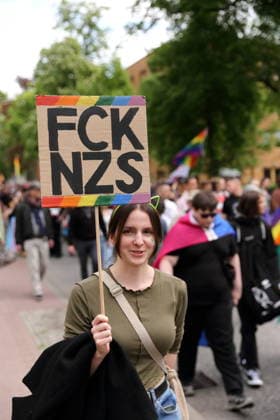 A person walks with a sign FCK NZS in the Pappelallee during a demo for Christopher Street Day in Potsdam, May 9, 2026 CSD in Potsdam