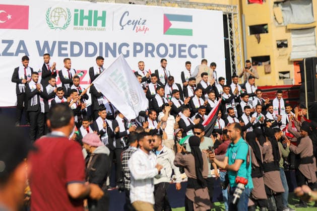 Mass Wedding Gaza City May 11 Grooms stand and clap on the steps of a stage beneath a banner reading Gaza Wedding Project during a mass wedding celebration in Gaza City, Gaza Strip, on May 11, 2026. The mass wedding celebration for 50 grooms, identified by organizers as orphans of conflict casualties, is sponsored by the Turkish Humanitarian Relief Foundation (IHH). Gaza Gaza Strip Palestinian Territories Copyright: xAhmedxAlxArinix
