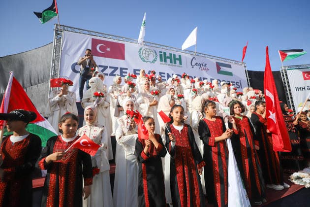 Mass Wedding Gaza City May 11 Girls wearing traditional embroidered dresses hold Turkish flags in front of a stage of brides during a mass wedding celebration in Gaza City, Gaza Strip, on May 11, 2026. The mass wedding celebration for 50 grooms, identified by organizers as orphans of conflict casualties, is sponsored by the Turkish Humanitarian Relief Foundation (IHH). Gaza Gaza Strip Palestinian Territories Copyright: xAhmedxAlxArinix