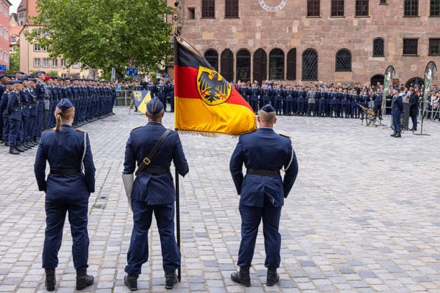 Public pledge of the Bundeswehr on Sebalder Platz, Nuremberg, 13 05 2026 Flag bearers present the troop flag with federal eagle in front of the recruits of the Germersheim Air Force Training Battalion In the foreground a female soldier as part of the flag delegation Nuremberg Bavaria Germany 20260513-286A7274-M4000