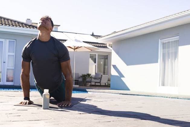 Man stretching back on paved poolside patio in dark sports shirt and shorts near water bottle, model released, property released, 27.03.2025 06:00:00, 11794033 Copyright: xIMS-260401xcreatorid:x333x 11794033