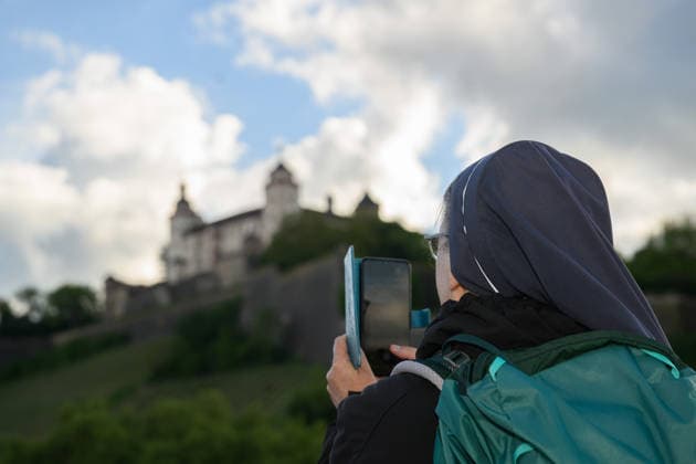 A nun takes a photo of the Marienberg Fortress from the Old Main Bridge at the Katholikentag in Wuerzburg Photo from 15 05 2026 Several tens of thousands of participants are expected to attend a total Copyright: epd-bild DanielxPeter epd-Katholikentag_Wuerzburg143-kopieren