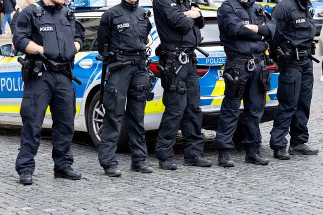 Augsburg, Bavaria, Germany May 16, 2026: Demonstration in Augsburg against the current federal government led by Chancellor Friedrich Merz. The slogan: Merz must go! Several police officers on duty in front of a patrol car