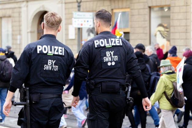 Augsburg, Bavaria, Germany May 16, 2026: Demonstration in Augsburg against the current federal government led by Chancellor Friedrich Merz. The slogan: Merz must go! Two police officers stand in front of passing demonstrators to maintain order