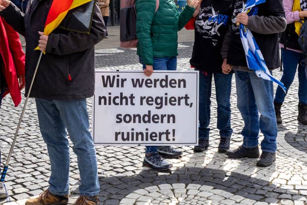 Augsburg, Bavaria, Germany May 16, 2026: Demonstration in Augsburg against the current federal government led by Chancellor Friedrich Merz. The slogan: Merz must go! A woman holds a sign reading: WE ARE NOT BEING GOVERNED, BUT RUINED!