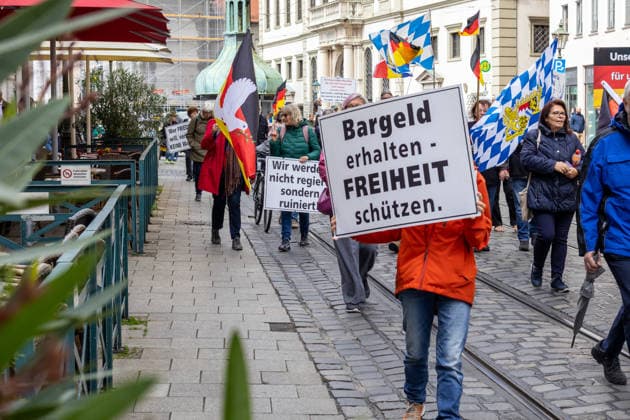 Augsburg, Bavaria, Germany May 16, 2026: Demonstration in Augsburg against the current federal government led by Chancellor Friedrich Merz. Under the slogan: Merz must go! Crowd holding a sign: CASH PRESERVES FREEDOM