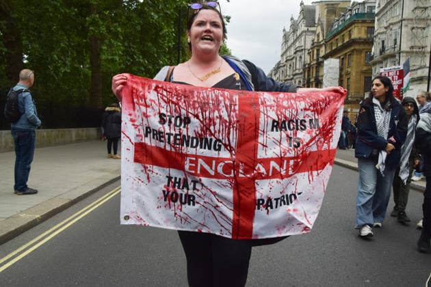 May 16, 2026, London, England, United Kingdom: A protester holds an English flag covered in fake blood and emblazoned with Stop pretending that your racism in patrotism as thousands of people take part in the Nakba 78 March For Palestine. The march commemorates 78 years of the Nakba and is also a protest against Tommy Robinson and the far right, who held their own Unite the Kingdom march at the same time. London United Kingdom  - ZUMAv130 20260516_zip_v130_047 Copyright: xVukxValcicx