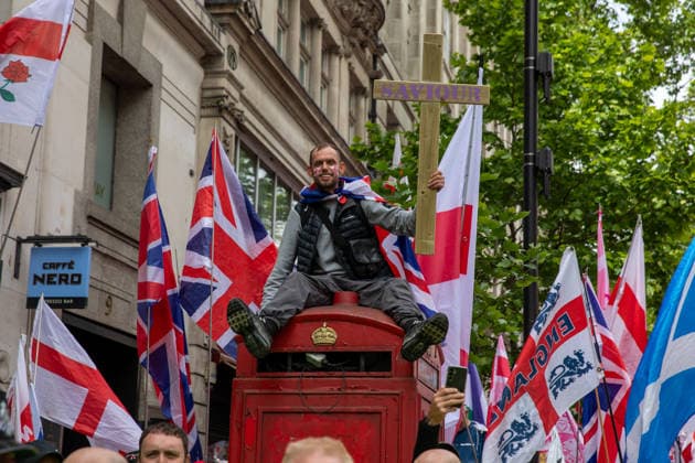May 16, 2026, London, United Kingdom: A Tommy Robinson supporter sits on a phone box whilst holding a cross during the Unite The Kingdom March and rally in London. The Unite the Kingdom march and rally held attracted large crowds to central London. Organized by Stephen Yaxley-Lennon, also known as Tommy Robinson, the event focused on immigration, border security, community cohesion and concerns surrounding radical Islam. Supporters described the rally as a defence of free speech, British Identity and national sovereignty, while critics said it risked deepening division and social tension within the United Kingdom. London United Kingdom  - ZUMAs197 20260516_aaa_s197_163 Copyright: xJamesxWilloughbyx