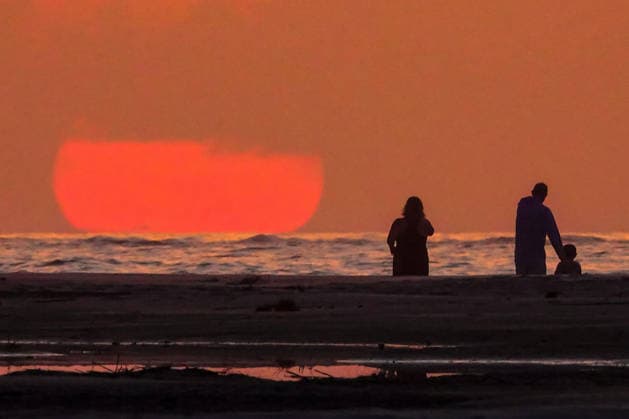 May 17, 2026, Isle Of Palms, Sc, United States: Beachgoers watch the giant orange sun climb above the Atlantic Ocean into a hazy sky at Wild Dunes resort, May 17, 2026 in Isle of Palms, South Carolina. Isle Of Palms United States - ZUMAe02_ 20260517_zaf_e02_002 Copyright: xRichardxEllisx