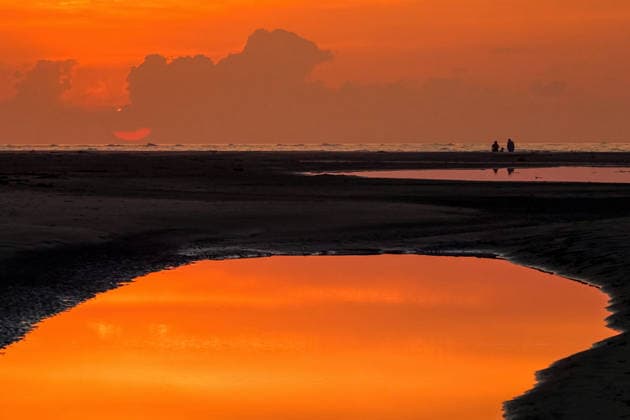 May 17, 2026, Isle Of Palms, Sc, United States: Beachgoers watch the giant orange sun climb above the Atlantic Ocean into a hazy sky reflected in a tidal pool along the beach at Wild Dunes resort, May 17, 2026 in Isle of Palms, South Carolina. Isle Of Palms United States - ZUMAe02_ 20260517_zaf_e02_004 Copyright: xRichardxEllisx