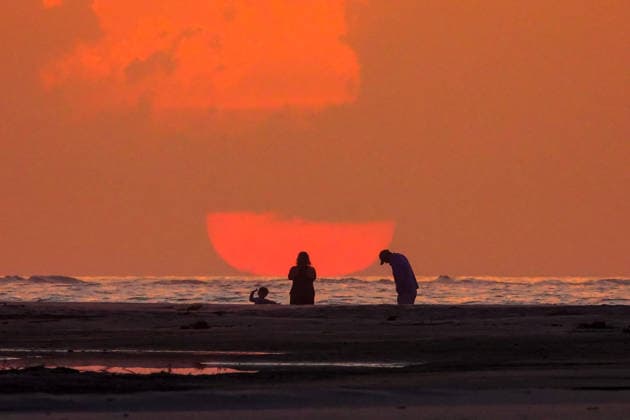 May 17, 2026, Isle Of Palms, Sc, United States: Beachgoers watch the giant orange sun climb above the Atlantic Ocean into a hazy sky at Wild Dunes resort, May 17, 2026 in Isle of Palms, South Carolina. Isle Of Palms United States - ZUMAe02_ 20260517_zaf_e02_005 Copyright: xRichardxEllisx