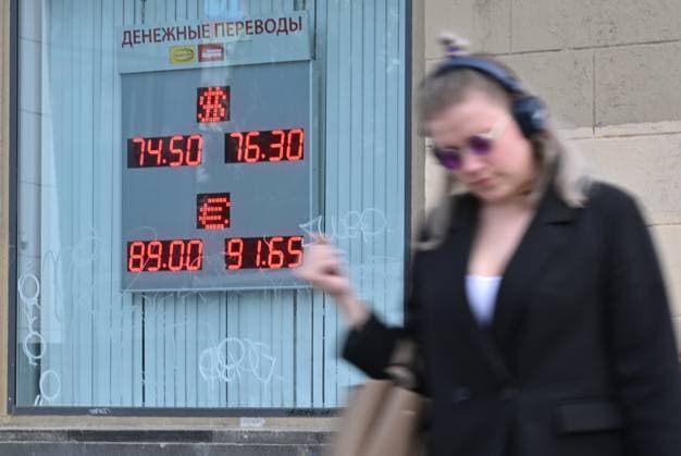 Russia Economy 9168303 18.05.2026 A young woman walks past a board showing currency exchange rates for the U.S. dollar and the euro against the Russian rouble in Moscow, Russia. Ilya Pitalev Sputnik Moscow Russia  Copyright: xIlyaxPitalevx