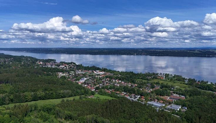 An early summers day near Tutzing, Starnberg district Here the view high above the Ilkahöhe to Oberzeismering, the village with Lake Starnberg and fair weather clouds.