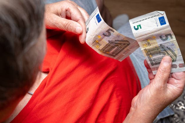 Bavaria, Germany May 20, 2026: An elderly woman of substantial build counts a few euro bills in her hands. The image symbolizes financial insecurity, poverty in old age, and the daily struggle with rising prices and a meager pension.