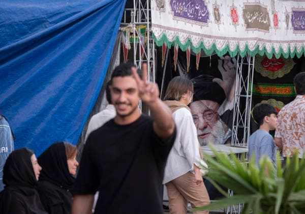 Daily Life In Iran Amid Threat About New Possible War A young Iranian man gestures with a Victory sign as he walks past a portrait of Iran s late Supreme Leader Ayatollah Ali Khamenei in a business district in downtown Tehran, Iran, on May 22, 2026. U.S. President Donald Trump has threatened Iran with the possibility of a new conflict, and according to official reports, he is considering military action if no agreement is reached with Iranian officials. Tehran Tehran Iran  Copyright: xMortezaxNikoubazlx originalFilename: nikoubazl-dailylif260522_np7UL