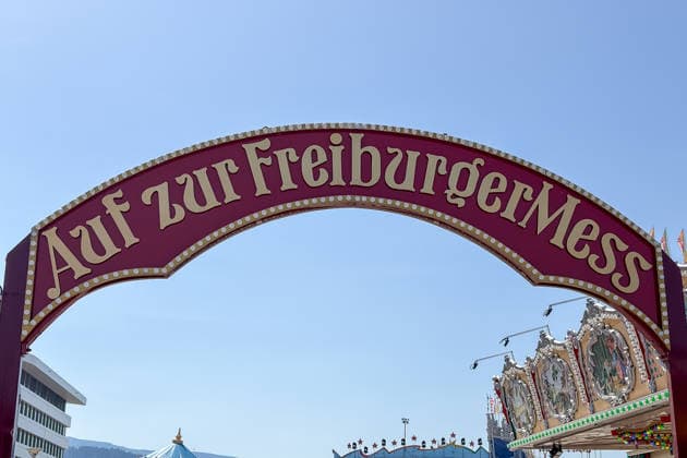 Freiburg im Breisgau GER, Freiburger Mess, Freiburg im Breisgau, 24 05 2026 The entrance archway to the Freiburger Mess under a blue sky, flanked by a modern building and a carousel Copyright: xEibner-Pressefoto ThomasxHessx
