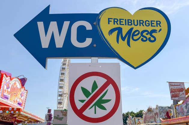 Freiburg im Breisgau GER, Cannabis ban at folk festival, Freiburg im Breisgau, 24 05 2026 Signpost to the Freiburger Mess and to the WCs, flanked by a cannabis prohibition sign, with rides in the background Copyright: xEibner-Pressefoto ThomasxHessx