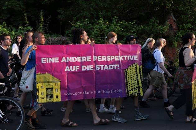 Demonstrators walk with banner A different perspective on the city City for all in the street Alter Tornow on the Hermannswerder peninsula during a demonstration against the eviction of the formerly squatted house Tornowstraße 40, Potsdam, May 26, 2026 Squatters demonstration in Potsdam