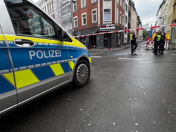 Police car in front of a cordoned-off street on Friesenwall in Cologne Several police officers stand behind a red and white barrier in front of the bar with their hazard lights on