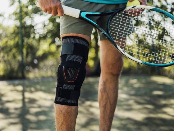 Tennis player wearing knee brace holding racket and ball outdoors model released, Symbolfoto, MFF10149