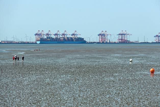 View from Friesenstrand beach in the North Sea resort of Tossens, a district of the municipality of Butjadingen in the district of Wesermarsch in Lower Saxony, of the North Sea bay of Jade Bay with dry mudflats In the background is the deep-water port Jade Weser Port JWP Wilhelmshaven The Wadden Sea is a UNESCO World Heritage Site