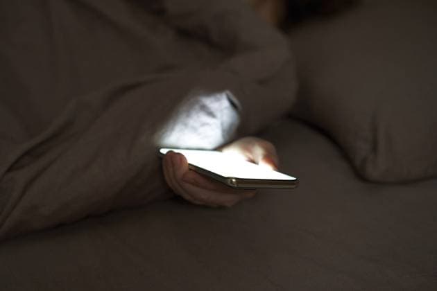 Weibliche Hand mit Smartphone, das im dunklen Schlafzimmer unter der Decke leuchtet Female hand holding smartphone glowing under blanket in dark bedroom setting Copyright: imageBROKER ElenaxSafonova ibxiqx17850741.jpg