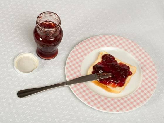 Spread jam on bread with knife and jar of jam. Pink checkered plate Copyright: xdeyan_georgievx Panthermedia69219064.jpg