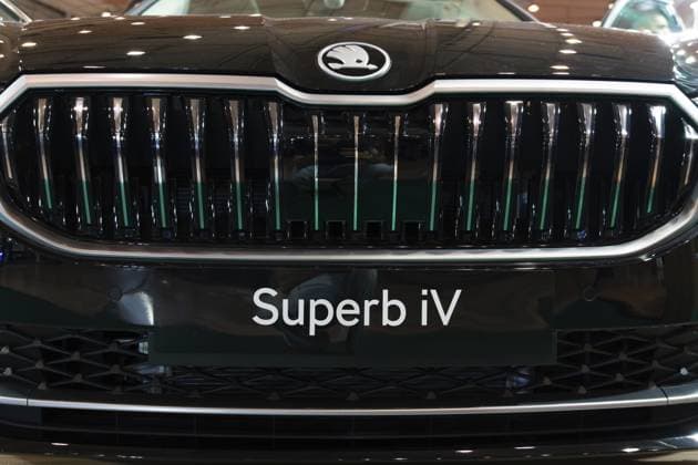 LISSABON, PORTUGAL — 16. MAI 2026: Symmetrische Nahaufnahme des verchromten Kühlergrills mit senkrechten Lamellen, der Emblem mit geflügelten Pfeilen und der Superb iV Platte an einem schwarzen Hybridauto auf der Ausstellung ECAR Show LISBON, PORTUGAL - MAY 16, 2026: Symmetrical front close-up of the chrome vertical slats radiator grille, winged arrow badge, and Superb iV plate on a black hybrid car at the ECAR Show exhibition Copyright: imageBROKER MaksimxZabarovskii iblmza18023246