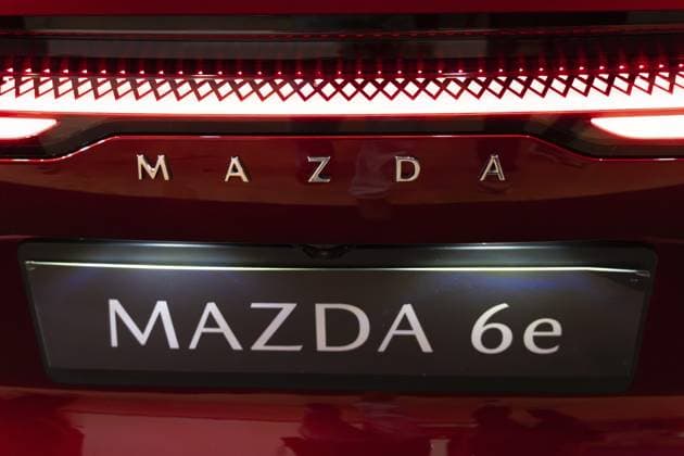 LISSABON, PORTUGAL, 16. MAI 2026: Symmetrische Nahaufnahme des verchromten Mazda Schriftzugs, des großen Mazda 6e Modellschilds und der beleuchteten roten LED Rücklichtleiste einer roten Elektro Limousine auf der ECAR Show LISBON, PORTUGAL, MAY 16, 2026: Symmetrical rear close-up of the chrome Mazda lettering, large Mazda 6e model plate, and illuminated red LED tail light bar on a red electric sedan at the ECAR Show Copyright: imageBROKER MaksimxZabarovskii iblmza18023265