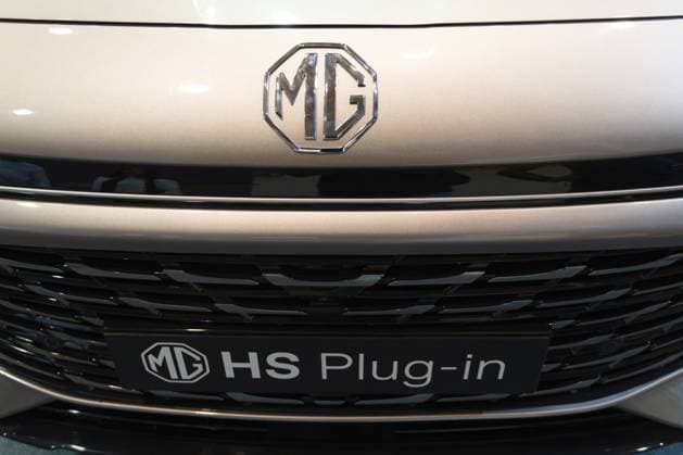 LISSABON, PORTUGAL — 16. MAI 2026: Symmetrische Nahaufnahme des achteckigen verchromten MG Emblems, des schwarzen strukturierten Kühlergrills und des MG HS Plug in Typenschilds auf einem silbernen Hybrid SUV auf der Ausstellung ECAR Show LISBON, PORTUGAL - MAY 16, 2026: Symmetrical front close-up of the octagonal chrome MG emblem, black textured grille, and MG HS Plug-in nameplate on a silver hybrid SUV at the ECAR Show exhibition Copyright: imageBROKER MaksimxZabarovskii iblmza18023267