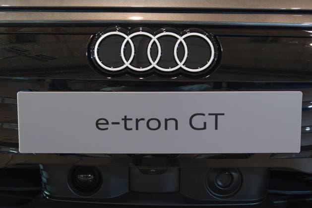 LISSABON, PORTUGAL — 16. MAI 2026: Symmetrische Nahaufnahme des beleuchteten verchromten Audi Vierringlogos und des weißen e tron GT Modellschilds auf einer glänzenden schwarzen Tafel auf der ECAR Show EV LISBON, PORTUGAL - MAY 16, 2026: Symmetrical close-up of the illuminated chrome Audi four rings logo and white e-tron GT model nameplate on a gloss black panel at the ECAR Show EV exhibition Copyright: imageBROKER MaksimxZabarovskii iblmza18023280