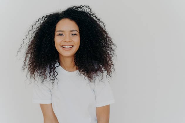 Eine fröhliche junge Frau mit lockigem Afro-Haar lacht fröhlich in einem weißen T-Shirt vor weißem Hintergrund Happy young woman with curly afro hair laughs joyfully wearing white t-shirt against white background (License=RF) ,model released, Symbolfoto Copyright: xZoonar.com ViorelxKurnosovx 25185695 ,model released, Symbolfoto ,property released