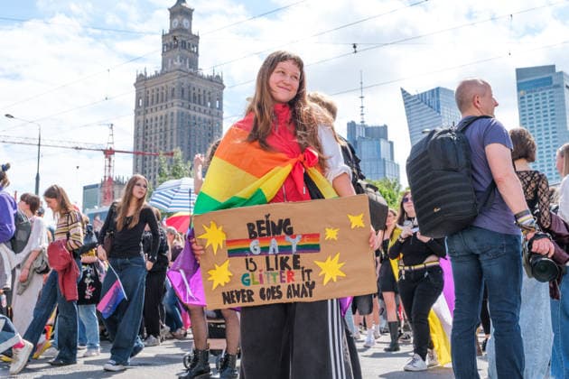 June 13, 2026, Warsaw, Masovian Voivodeship, Poland: A person wearing a rainbow flag holds a sign that reads being gay is like glitter, it never goews away during the 25th annual Warsaw LGBTQ+ Pride Parade, known in Polish as the Equality Parade. LGBTQ+ people in Poland do not have the right to same-sex civil partnerships, marriage, and child adoption, while also facing homophobia and queerphobia from a largely conservative society. Therefore, the parade is organized primarily as a march for equal rights. Warsaw Poland - ZUMAk204 20260613_zip_k204_004 Copyright: xRomanxKozielx