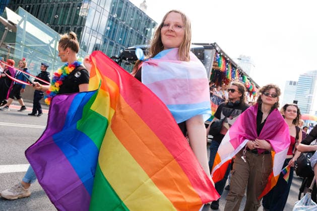 June 13, 2026, Warsaw, Masovian Voivodeship, Poland: A person draped in a trans pride flag carries a rainbow flag during the 25th annual Warsaw LGBTQ+ Pride Parade, known in Polish as the Equality Parade. LGBTQ+ people in Poland do not have the right to same-sex civil partnerships, marriage, and child adoption, while also facing homophobia and queerphobia from a largely conservative society. Therefore, the parade is organized primarily as a march for equal rights. Warsaw Poland - ZUMAk204 20260613_zip_k204_007 Copyright: xRomanxKozielx