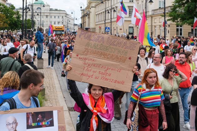 June 13, 2026, Warsaw, Masovian Voivodeship, Poland: A person marches with a large sign that reads Poland recognizes same-sex marriage only under the conditions of travel abroad for the marriage , 7 years of court battles and residency in Warsaw during the 25th annual Warsaw LGBTQ+ Pride Parade, known in Polish as the Equality Parade. LGBTQ+ people in Poland do not have the right to same-sex civil partnerships, marriage, and child adoption, while also facing homophobia and queerphobia from a largely conservative society. Therefore, the parade is organized primarily as a march for equal rights. Warsaw Poland - ZUMAk204 20260613_zip_k204_016 Copyright: xRomanxKozielx