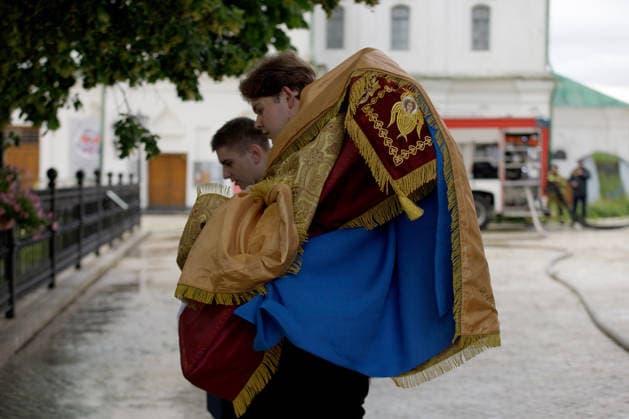 Two young men hold religious banners at the Kyiv Pechersk Lavra, where the roof of the Dormition Cathedral caught fire during a massive Russian combined attack, Kyiv, Ukraine, June 15, 2026. The Russian army launched a large-scale assault on the Ukrainian capital with missiles and strike drones, killing four people and injuring 28, including children and a pregnant woman. At least 140,000 consumers were left without electricity due to damage to power grids. Residential buildings, the Kyiv Pechersk Lavra, the Mystetskyi Arsenal Museum Complex, the Dovzhenko Film Studio, and the building of the High Anti-Corruption Court sustained damage. (Photo by Marianna Kotyk Ukrinform) Massive Russian attack damages Kyiv Pechersk Lavra and Mystetskyi Ars  Copyright: xMariannaxKotykx