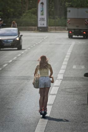 E-scooters, a young girl, and a little boy are riding e-scooters. Individuals aged 14 and older are permitted to ride their own electric scooters, and those aged 18 and older are permitted to ride rental scooters. Use by children under 14: 90 euros, 1 point, Berlin E-