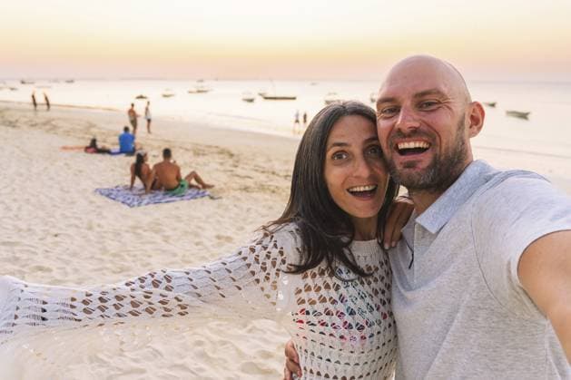 Glückliches Paar macht Strand Selfie bei Sonnenuntergang, Sansibar, Tansania, Küste des Indischen Ozeans, tropischer Urlaub, Romantik, Reiselfestyle, unvergesslicher Urlaub Happy couple taking beach selfie during sunset, Zanzibar Tanzania, Indian Ocean coastline, tropical vacation, romance, travel lifestyle, memorable holiday Copyright: imageBROKER EvaldasxMikoliunas ibxemi18238322.jpg ,model released, Symbolfoto ,property released