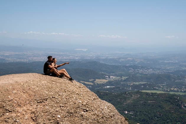 Couple sits on a mountain cliff pointing at the valley in Spain model released, Symbolfoto property released, PNAF07065