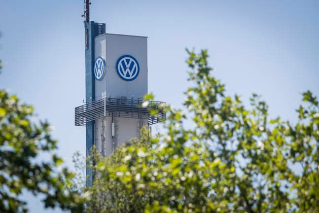 Tower at the VW plant in Osnabrück with the VW logo against a blue sky, framed by the foliage of green trees; stock photo: Volkswagen Osnabrück, July 11, 2026; stock photo: VW Osnabrück