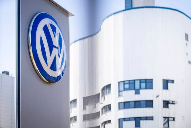 Stock photo: Volkswagen Osnabrück—VW logo at Gate 2, photographed through the fence with a white factory building in the background; VW plant in Osnabrück, July 11, 2026; stock photo: VW Osnabrück