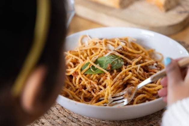 Child holding fork with turquoise nails, twirling spaghetti with basil in white bowl at table, model released, property released, 03.07.2025 06:00:00, 6981104 Copyright: xIDS-260427_1xcreatorid:x0x 6981104